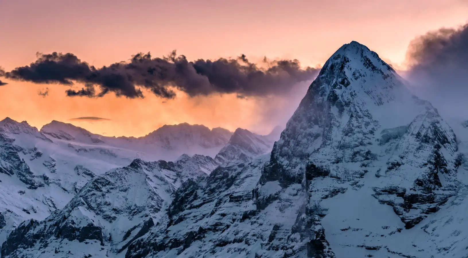 Majestic snow-covered Swiss mountain at sunset with glowing alpine sky, capturing the beauty explored through the Best place to buy swiss travel pass.