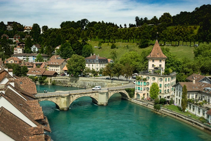 A bridge over a river with buildings and trees in Switzerland