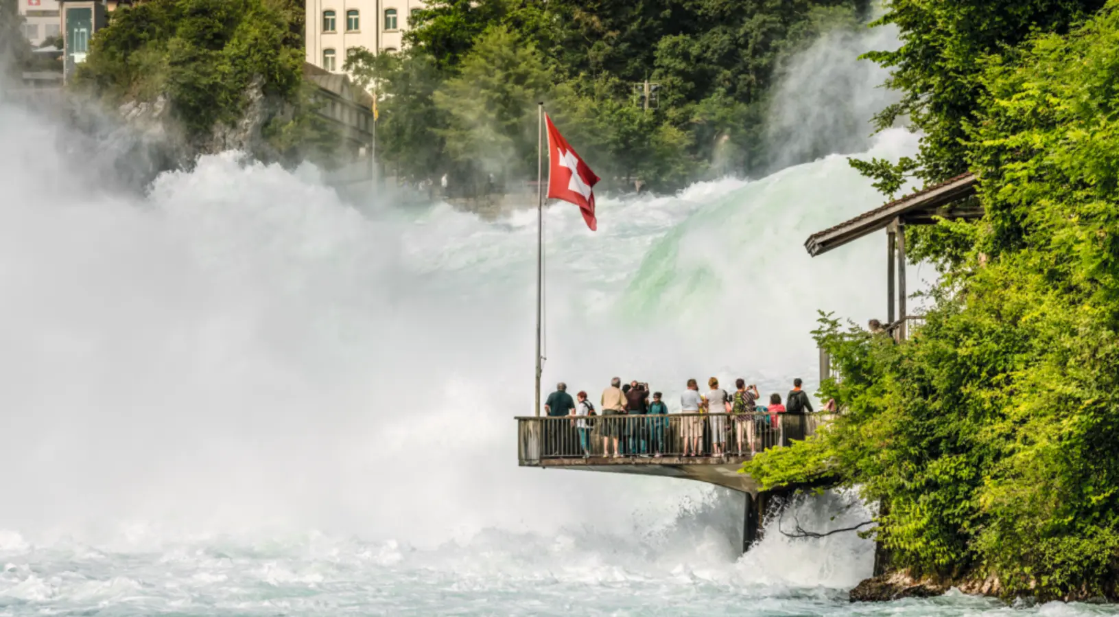 Crowd of people enjoying a waterfall in Switzerland. The majority of Waterfalls in Switzerland are connected by Swiss Rail, which is free with a Swiss Travel Pass. This is why it is essential to know how to use the Swiss Travel Pass.
