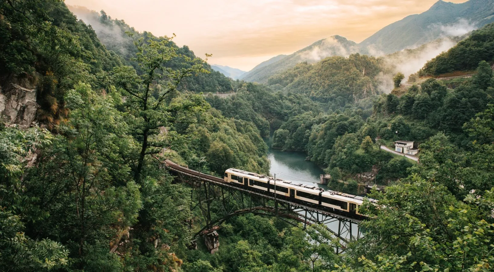 Swiss regional train crossing a high bridge surrounded by lush green forests, demonstrating travel coverage in How the Swiss Travel Pass Works on Trains.