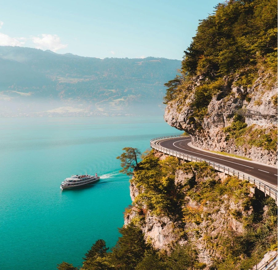 A cruise boat on the calm waters of Lake Thun, surrounded by Swiss mountains.