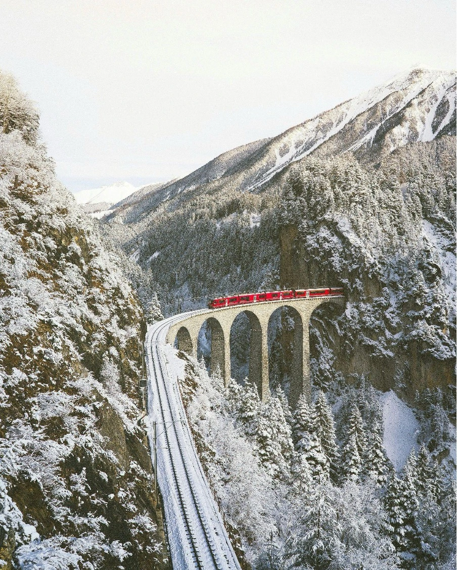 The Bernina Express crossing the iconic Landwasser Viaduct in Switzerland.