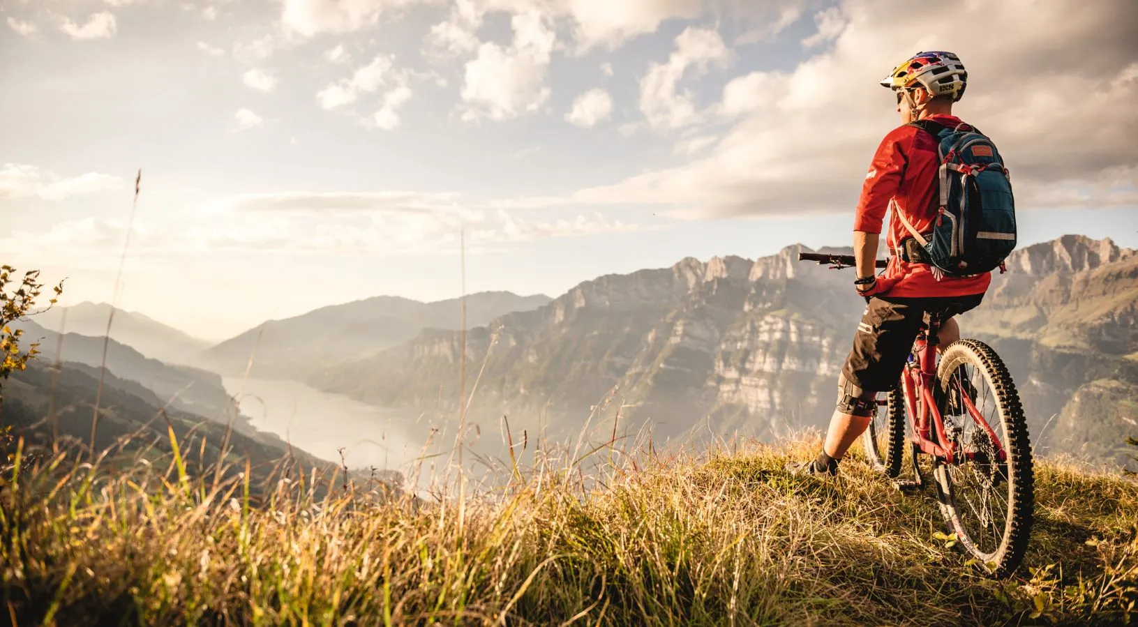 Swiss Alps view with a cyclist overlooking the lake, showcasing experiences covered by the Swiss Travel Pass 3, 4 or 8 days