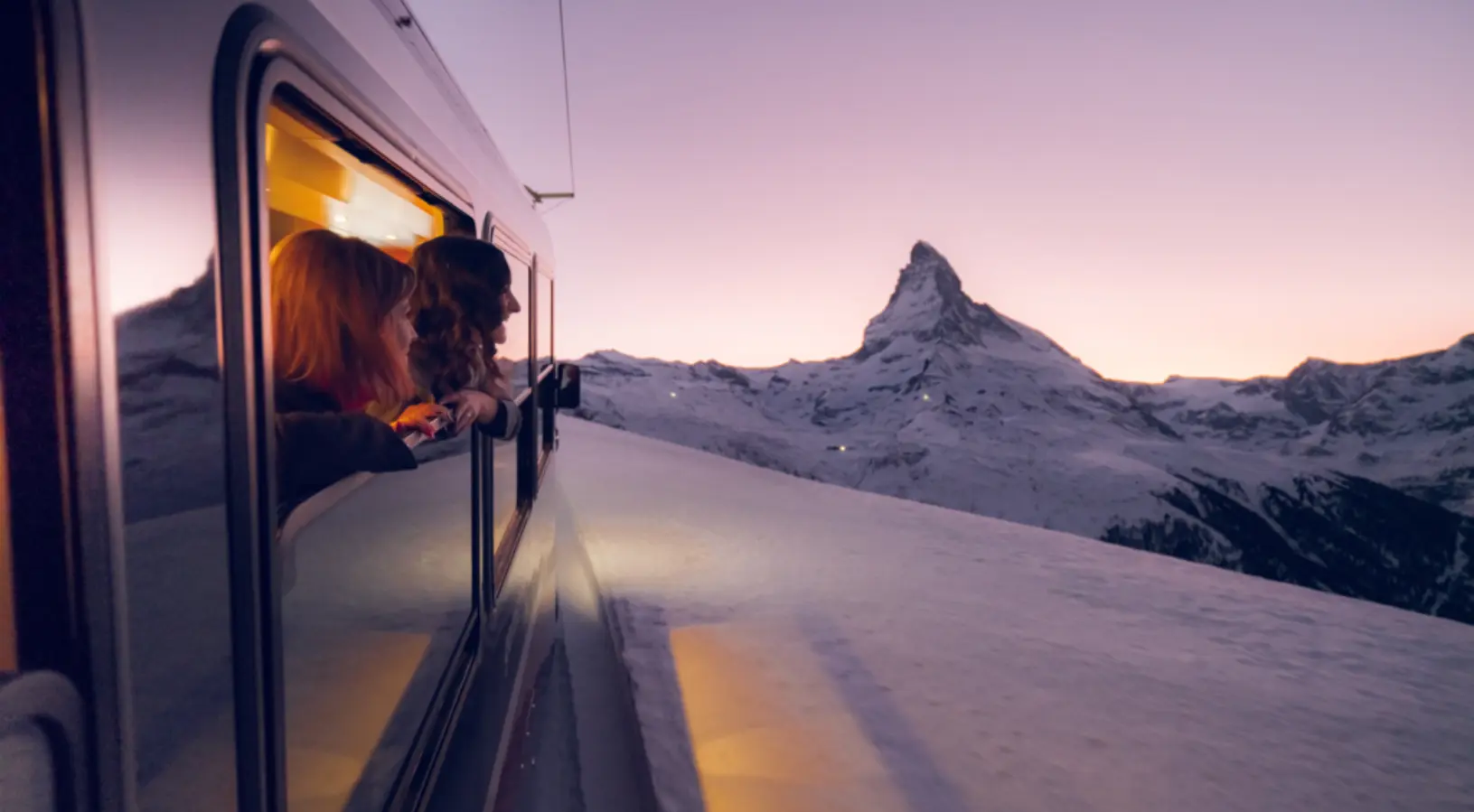 Two girls enjoying the Swiss Rail, looking out of the train’s window