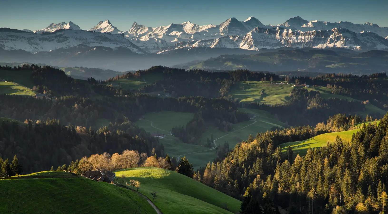 A panoramic view of the Swiss Alps with sharp glacier-capped peaks under a vivid blue sky, indicating that the best time to visit Switzerland is when the alpine scenery is most accessible for outdoor exploration.