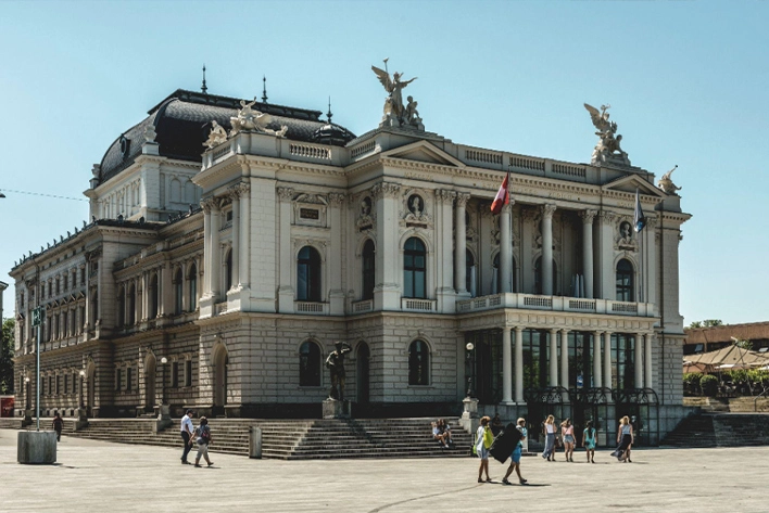 The Zurich Opera House in Switzerland with people walking around.