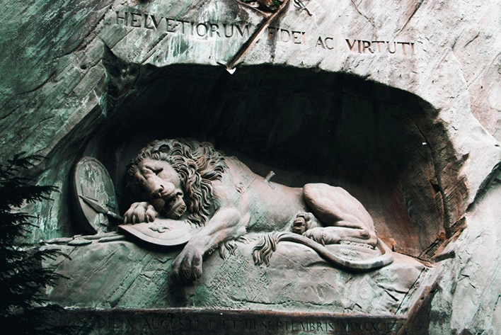 Close-up of the Lion Monument in Lucerne, Switzerland, depicting a dying lion carved into a sandstone rock, symbolizing bravery and mourning for Swiss Guards who died during the French Revolution.